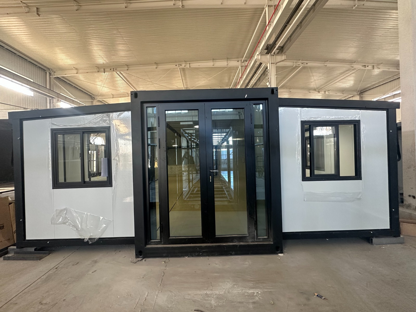 40ft expandable prefab container home fully expanded showing black frame, white panels and large glass front door